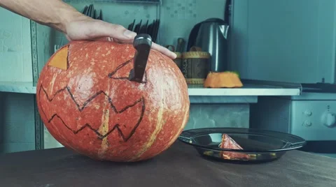 Young men carves jack o lantern out of pumpkin on a kitchen table using knife Stock Footage 68309914