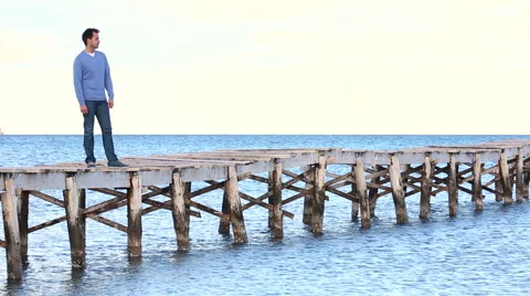 Young men engrossed in thought throwing stones into the water Stock Footage 57764648