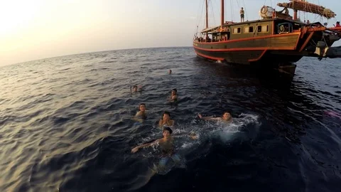 Young men having fun in ocean near boat Stock Footage 77717588