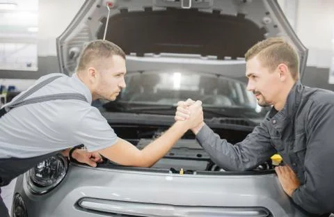 Young men making a deal between each other. They lean to car and hold each ot Stockfoto's