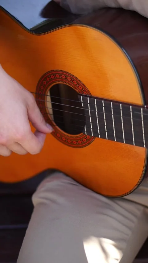 Young men is playing acoustic guitar outside Stock Footage 283576264