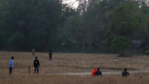 Young men playing cricket in an open rural field in Assam, India Stock Footage 326987910