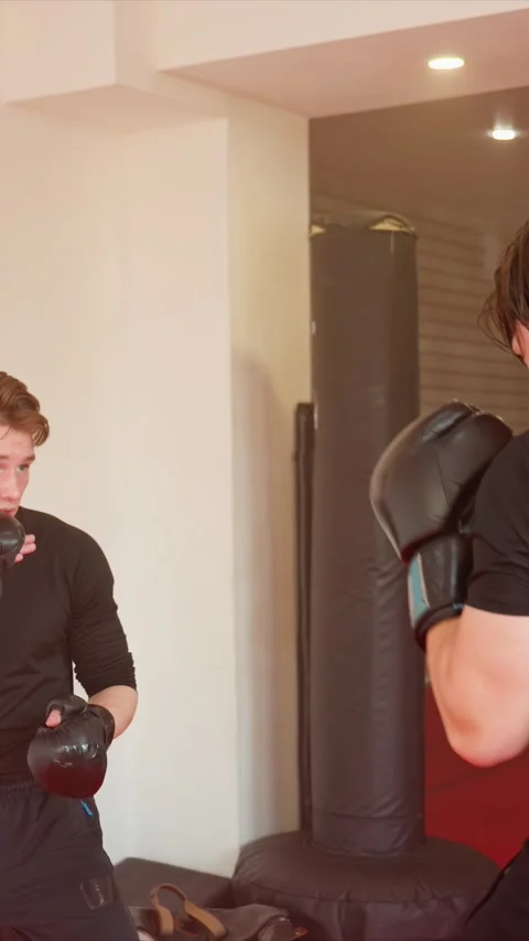 Young men practicing boxing indoors wearing black attire and gloves in gym Stock Footage 343092639