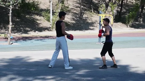 Young men practicing boxing moves outdoors on sports ground with exercise Stock Footage 318665782