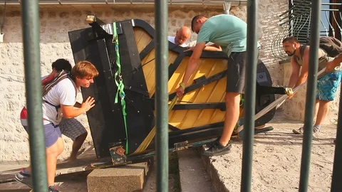 Young men pulling piano on the street of the old city Stock Footage 102793644
