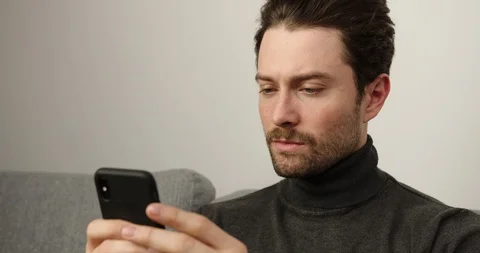 Young men relaxing on couch using smart phone in house. Young guy write sms , a Stock-Footage 123525085