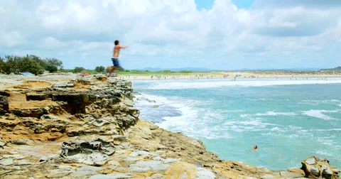 Young men run and jump from Cliff Stock Footage 58190975