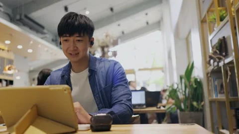 A young men sitting in a cafe. She is attending a video conference and talks  Stock Footage 247040353