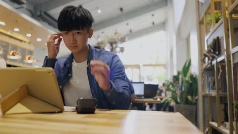 A young men sitting in a cafe. She is attending a video conference and talks  Stock Footage 247040417