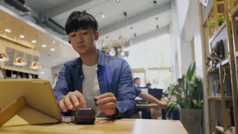 A young men sitting in a cafe. She is attending a video conference and talks  Stock Footage 247040498