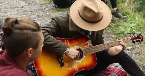 Young men sitting on ground and playing guitar Stock-Footage 94860733