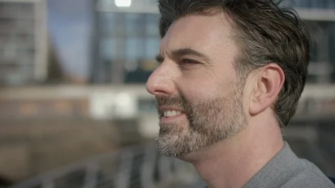 Young men is smiling into the distance while wind is blowing through his hair Stock Footage 97849293