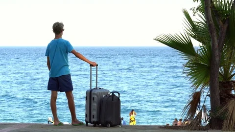 Young men on a tropical beach with suitcase Stock Footage 80363778