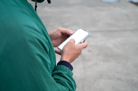 Young men is typing on a smartphone screen while holding a phone in his hands on Stock Photos