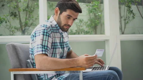Young men using credit cards to buy items online via laptop computer.  handso Stock Footage 134398855