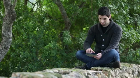 Young men using digital tablet in  a green park Stock Footage 44939481