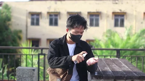 Young men using hand sanitizer at outdoor city park Stock Footage 169356258