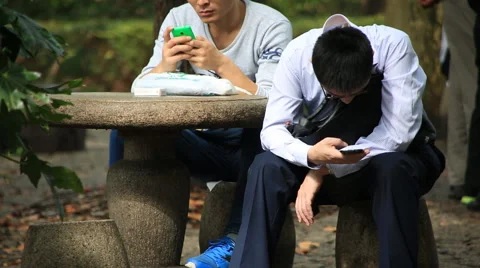 Young men using smart phones at People's square park in Shanghai, China Stock Footage 56802267