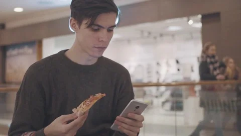 Young men using smartphone eat pizza and drink coke at shopping mall. Portrait Stock Footage 70185343