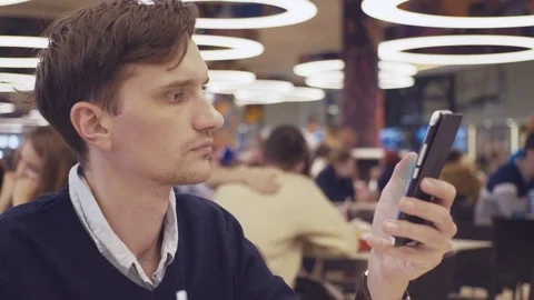 Young men using smartphone at food court in shopping mall. Portrait Video stock 70152543