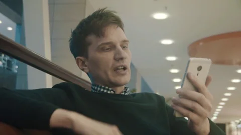 Young men using smartphone making video call at lobby of shopping mall. Portrait Stock Footage 76045782