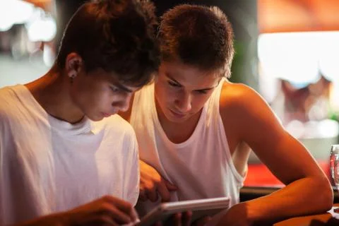 Young men using tablet computer in cafe Photos