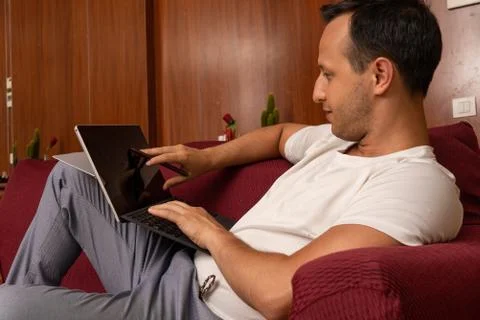 Young men using tablet at home alone while resting on the sofa Stock Photos