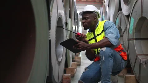 A young men working in a warehouse storing rolls of metal sheets. Video stock 254765891