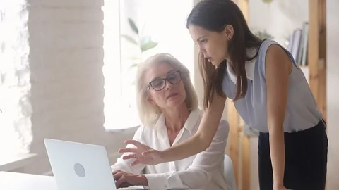 Young mentor manager helping old worker explaining computer work instructing Stock Footage 107724383