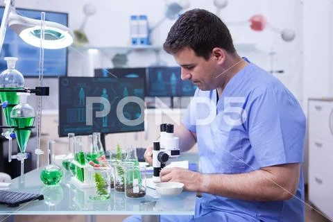 Young microbiologist working on his microscope in a research lab Stock Photos