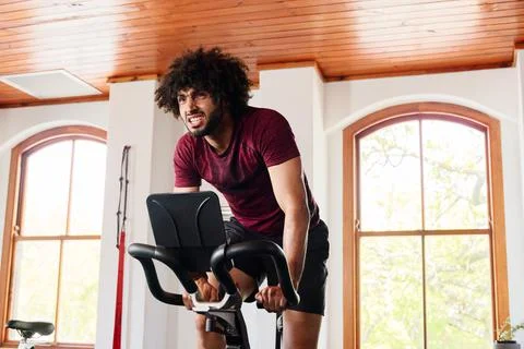 Young middle eastern man doing intense cardio workout on exercise bike at the Stock Photos