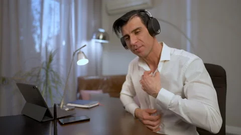 Young Middle Eastern man putting on headphones and turning on webcamera sitting Stock Footage 153689282