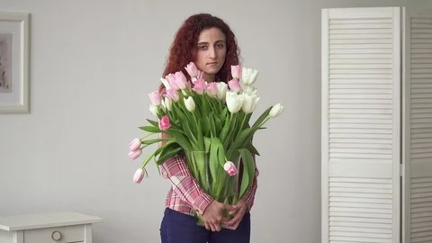 Young middle eastern woman with sad eyes holding flowers in hands at home Stock Footage 87332996