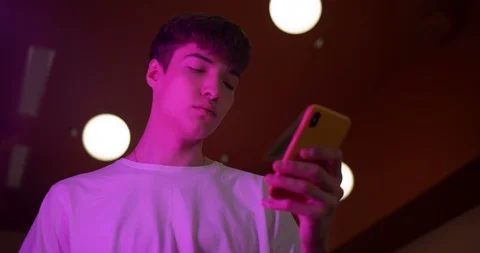 Young Millenial Guy Wearing White T-Shirt Using his Smartphone Standing at Stock Footage 118877832