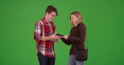Young millennial couple taking selfies together on cellphone on green screen Video stock 79385574