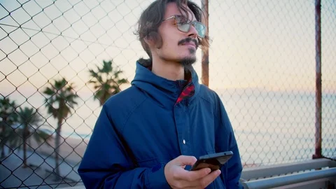 Young millennial hipster man with red glasses using mobile phone smartphone app Stock-Footage 100861369