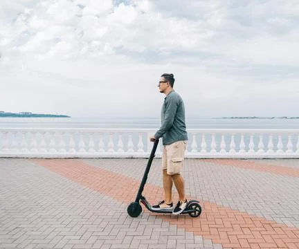 Young millennial man while riding on the electric scooter. Stock Photos