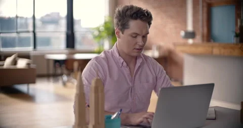 Young millennial works diligently on computer typing on laptop in urban office 스톡 동영상 167045776