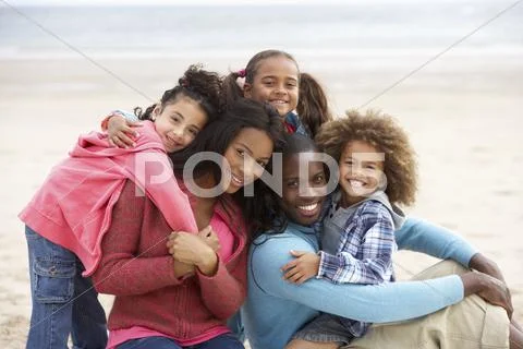 Young mixed race family embracing on beach Stock Photos