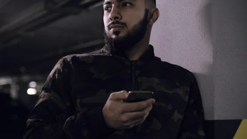 Young mixed race man with a beard is holding a smartphone Video stock 112276031