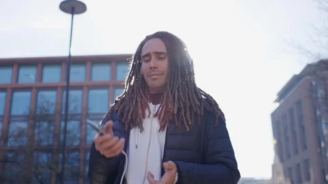 Young mixed race man with dreadlocks dancing to music from his headphones Stock Footage 103850839