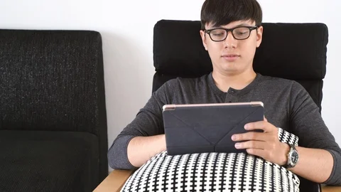 Young mixed race millennial man reading and studying on digital tablet in liv Stock-Footage 112002743