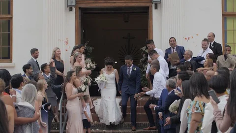 Young, mixed race wedding couple, just married, exiting the church and Stock Footage