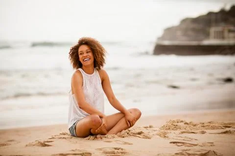 Young mixed-race woman stting on the beach Stock Photos