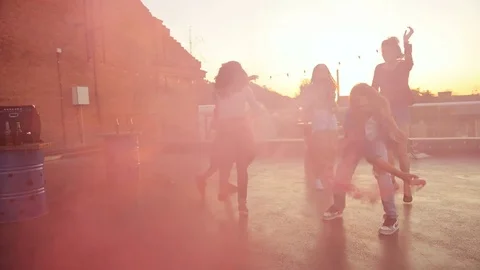 Young mixed raced friends playing with pink smoke grenade at the rooftop party Stock Footage 81803908