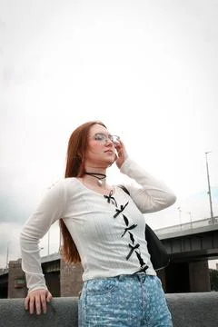 A young model in light-colored jeans walks around the city. Mild spring weather. Stock Photos
