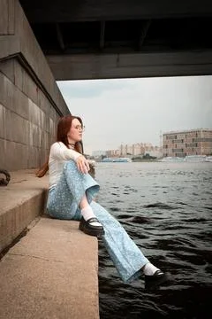 A young model in light-colored jeans walks around the city. Mild spring weather. Stock Photos