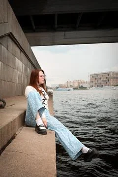 A young model in light-colored jeans walks around the city. Mild spring weather. Stock Photos
