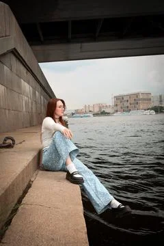 A young model in light-colored jeans walks around the city. Mild spring weather. Stock Photos
