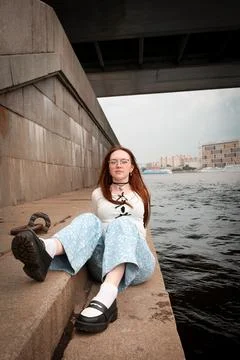A young model in light-colored jeans walks around the city. Mild spring weather. Stock Photos
